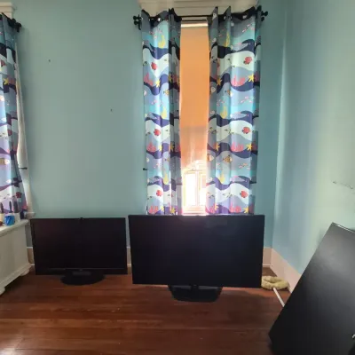Sale Photo Thumbnail #93: Two black flat-screen televisions sitting on a hardwood floor, paired with colorful ocean-themed window curtains.