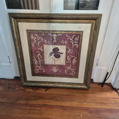 Sale Photo Thumbnail #43: Large framed botanical art print depicting a dark iris flower with scrolled scrollwork borders in an ornate gold frame.