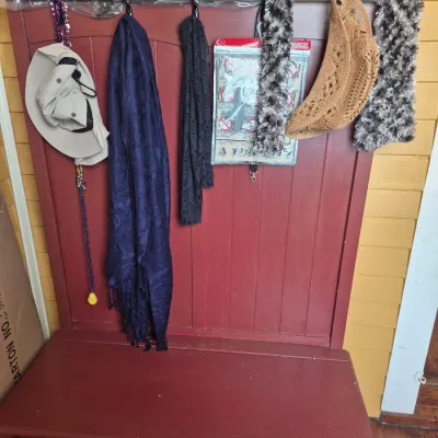 Sale Photo Thumbnail #106: Red painted wooden hall tree storage bench with hanging hooks, displayed with hats and scarves.