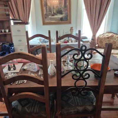 Sale Photo Thumbnail #61: Rustic wooden dining table and chair set with patterned fabric cushions, surrounded by household decor and small collectibles.