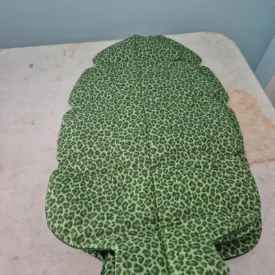 Sale Photo Thumbnail #110: Stack of green leopard print quilted patio chair or lounger cushions, shaped to fit high-back seating.
