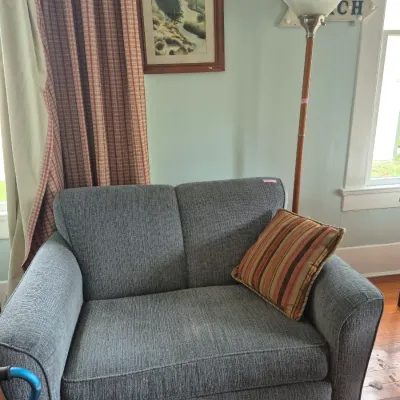 Sale Photo Thumbnail #51: Contemporary oversized gray upholstered armchair with striped throw pillow, standing next to a floor lamp and framed wall art.