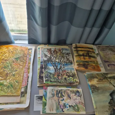 Sale Photo Thumbnail #75: Collection of unframed landscape and abstract watercolor paintings arranged on a tabletop.