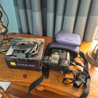 Sale Photo Thumbnail #71: Nikon Coolpix S3000 digital camera in original box paired with a vintage Ricoh Mirai 105 35mm bridge camera and carrying case.
