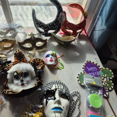 Sale Photo Thumbnail #80: Assortment of Mardi Gras masks and decorative items, including elaborate sequined eye masks, porcelain face masks, and themed party favors.
