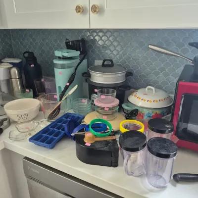Sale Photo Thumbnail #16: Assorted modern kitchen counter items including a Keurig coffee maker, electric steamer pot, glass prep bowls, and personal blender cups.