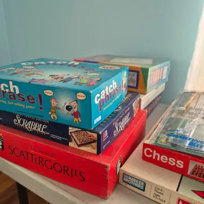 Sale Photo Thumbnail #109: Stack of vintage and modern board games including Catch Phrase, Scrabble, Scattergories, Monopoly, and Chess.