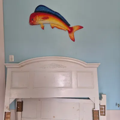 Sale Photo Thumbnail #101: Off-white wooden headboard and footboard with carved details, alongside a colorful painted mahi-mahi fish wall hanging.
