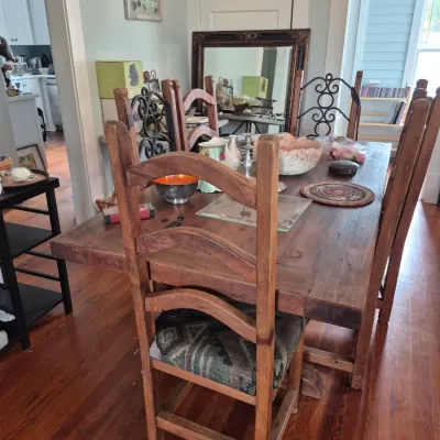 Sale Photo Thumbnail #45: Rustic wood dining table set with matching ladder-back chairs featuring upholstered seat cushions, complemented by decorative home goods and a large dark wood framed mirror.