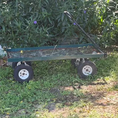 Heavy-duty green metal utility garden cart with a wire mesh bed and pneumatic tires.