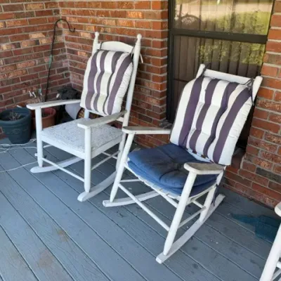Pair of white wooden outdoor rocking chairs with striped back cushions and blue seat pads.