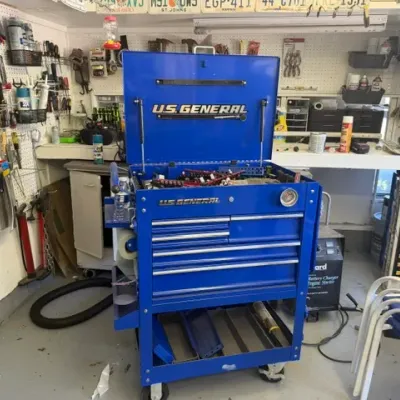 Blue U.S. General rolling mechanic's tool cart with a top lid, multiple drawers, side accessories, and a bottom shelf.