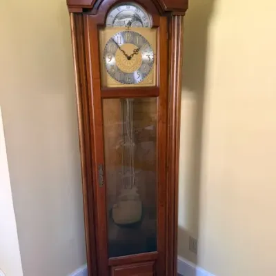 Traditional wooden grandfather clock with swan neck pediment, moon phase dial, and glass display door.