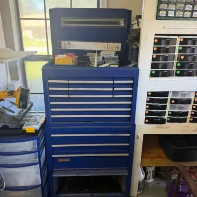 Tall blue metal tool chest combo featuring a top chest with a flip lid and multiple drawers resting on a rolling bottom cabinet.