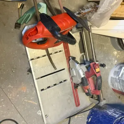 Collection of power tools and workshop equipment, including a wet tile saw and an electric hedge trimmer, showing signs of prior use.