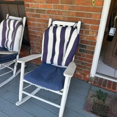 Pair of white wooden outdoor rocking chairs with navy and white striped back cushions and blue seat pads.