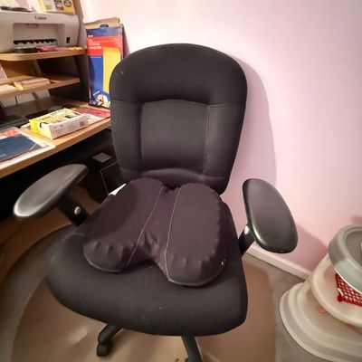Black fabric ergonomic office desk chair with armrests and an added seat cushion.