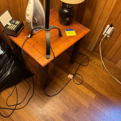 Sale Photo Thumbnail #88: Square wooden end table holding a black ceramic table lamp, modern clothes iron, small black electronic box, and a tripod-base lamp fixture.