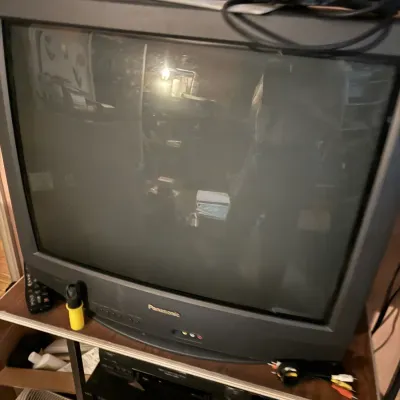 Sale Photo Thumbnail #72: Vintage Panasonic black CRT television with front-facing A/V ports, sitting on a media stand above stereo components.