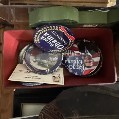 Sale Photo Thumbnail #130: A red felt-lined tray containing Barack Obama 2008 presidential campaign pinback buttons and various small ephemera.