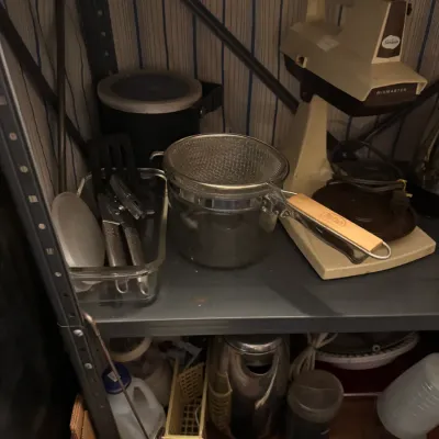 Sale Photo Thumbnail #73: Vintage Sunbeam Mixmaster stand mixer paired with various kitchen items including a mesh sifter, utensils, and glassware stored on metal shelving.