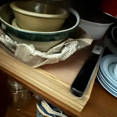 Sale Photo Thumbnail #117: Collection of ceramic mixing bowls, plates, and blue-and-white porcelain soup spoons stored inside a dark wood cabinet shelf.