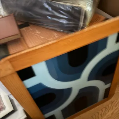 Sale Photo Thumbnail #141: A light wood hamper or storage bin featuring a retro blue geometric graphic panel, filled with packaged linens and books.