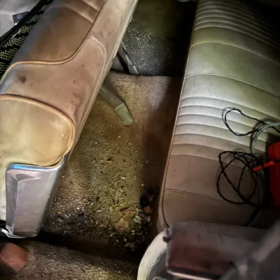 Sale Photo Thumbnail #28: Interior view of a vintage automobile featuring ribbed vinyl bench seats and carpeted flooring in worn, project condition.