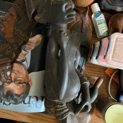 Sale Photo Thumbnail #129: Hand-carved dark wood African figure with detailed facial features and headdress, shown alongside other carved wooden masks and decor items.