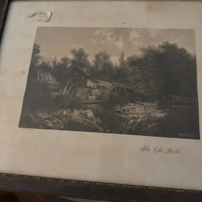 Sale Photo Thumbnail #142: Framed antique sepia print titled "The Old Mill," housed in a dark wooden frame with beaded inner trim. The matting shows visible age, staining, and surface damage in the upper left corner.