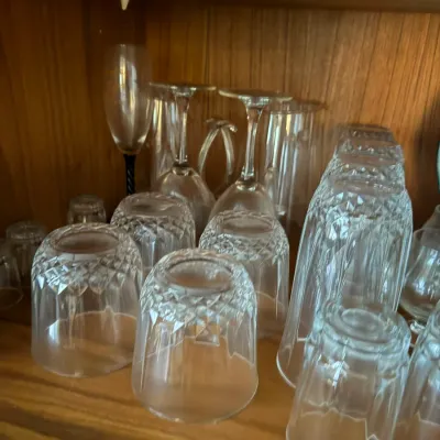 Sale Photo Thumbnail #111: Assortment of vintage cut glass drinking glasses, goblets, and wine flutes stored on a wooden shelf.