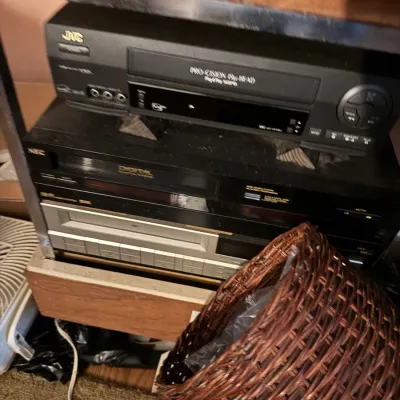 Sale Photo Thumbnail #10: Stack of vintage electronics including a JVC Pro-Cision VCR and other audio/video components stored on a shelf.