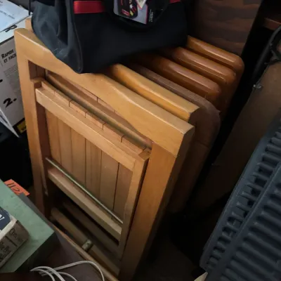Sale Photo Thumbnail #19: Set of folded wooden TV tray tables stacked behind a black tool bag.