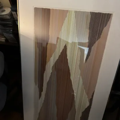 Sale Photo Thumbnail #20: Large framed abstract artwork in earth tones featuring a vertical linear and torn-paper style pattern, presented in a simple metal frame with white matting.