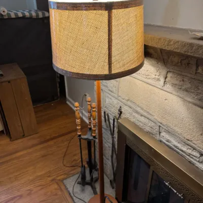 Sale Photo Thumbnail #23: Mid-century wooden floor lamp featuring a slender turned pole, round base, and a woven burlap drum shade.