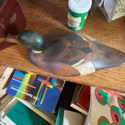 Sale Photo Thumbnail #123: Handcrafted intarsia wooden duck figurine resting on a shelf above vintage IBM Systems Journals and other manuals.