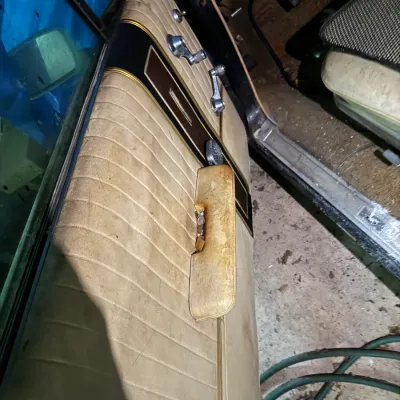 Sale Photo Thumbnail #30: Vintage vehicle interior featuring a beige vinyl driver's door panel with chrome window cranks and woodgrain trim, showing heavy wear and staining.