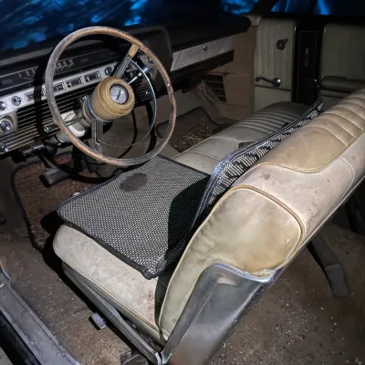 Sale Photo Thumbnail #29: Interior view of a vintage 1960s automobile, featuring a worn leather bench seat, a weathered steering wheel, and original dashboard detailing.
