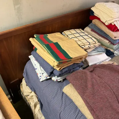 Sale Photo Thumbnail #38: Assorted stacks of vintage bed linens, towels, and blankets arranged on a wooden bed frame.