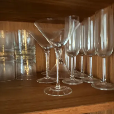 Sale Photo Thumbnail #108: Collection of clear glassware inside a wooden cabinet, including martini glasses, champagne flutes, and tumblers.