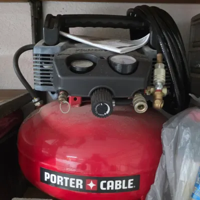 Porter-Cable pancake air compressor with attached hose and instruction manual.