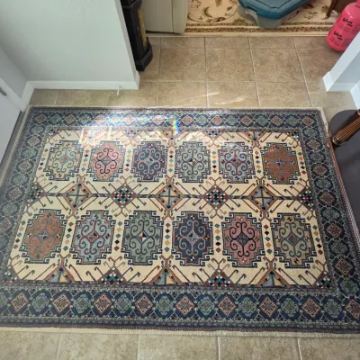 Traditional Caucasian or tribal style area rug featuring geometric medallions and motifs in shades of blue, pink, green, and cream with a...