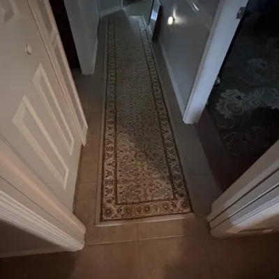 Traditional oriental-style runner rug with a beige ground, intricate floral medallion pattern, and ornate border, laid in a hallway.
