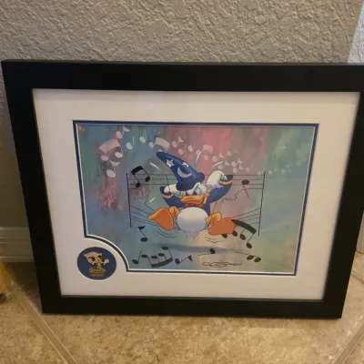 Framed Disney art print featuring Donald Duck as the Sorcerer's Apprentice, professionally matted in a black frame with a...