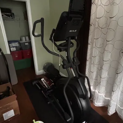Sole Fitness modern black elliptical machine positioned on a protective floor mat inside a home.