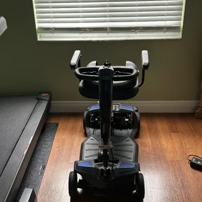 Pride Mobility four-wheel electric mobility scooter in black and blue, viewed from the front.