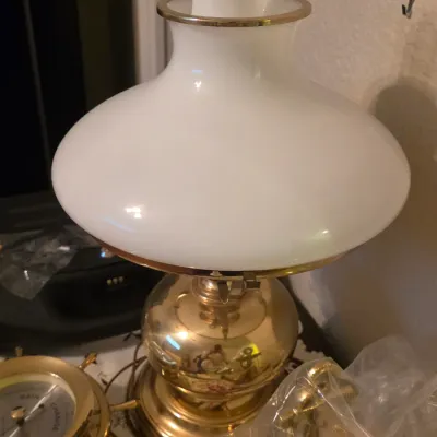 Vintage hurricane-style table lamp featuring a polished brass base and a white milk glass shade with gold rim trim.