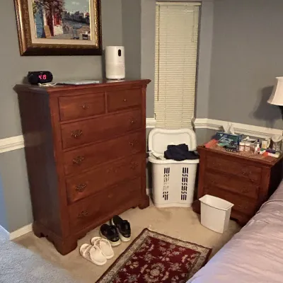 Traditional cherry wood bedroom furniture set featuring a tall chest of drawers and a matching nightstand with brass hardware.
