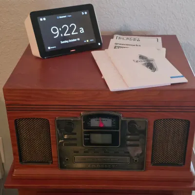 Crosley retro-style wooden music center with CD recorder, topped with a digital clock display and instruction manuals.