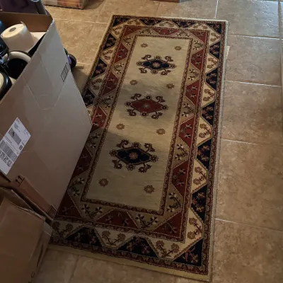 Traditional patterned runner rug featuring a beige center field with geometric medallions framed by red and navy ornate borders.